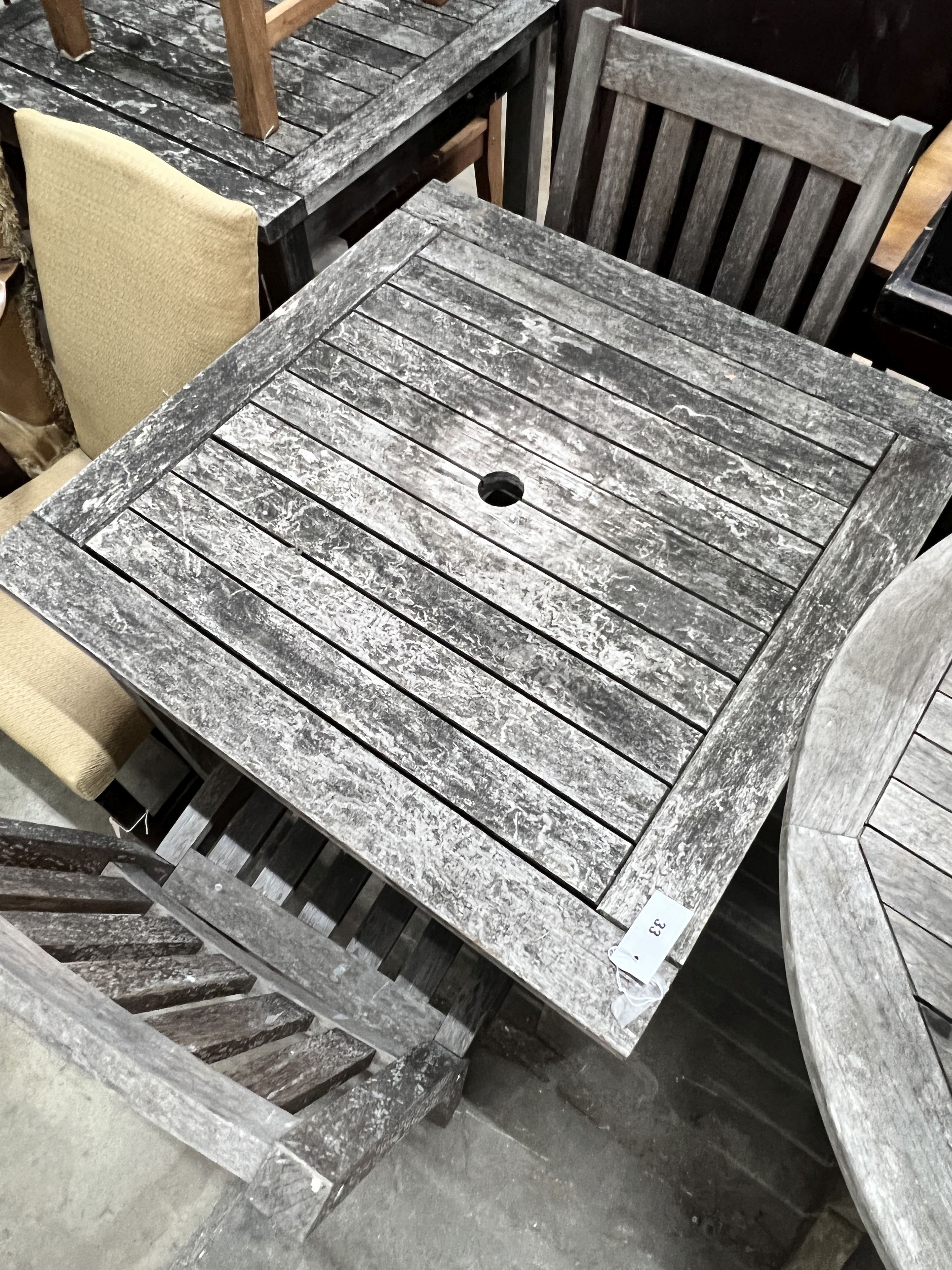 A square weathered teak garden table, width 80cm, height 73cm together with two teak garden chairs